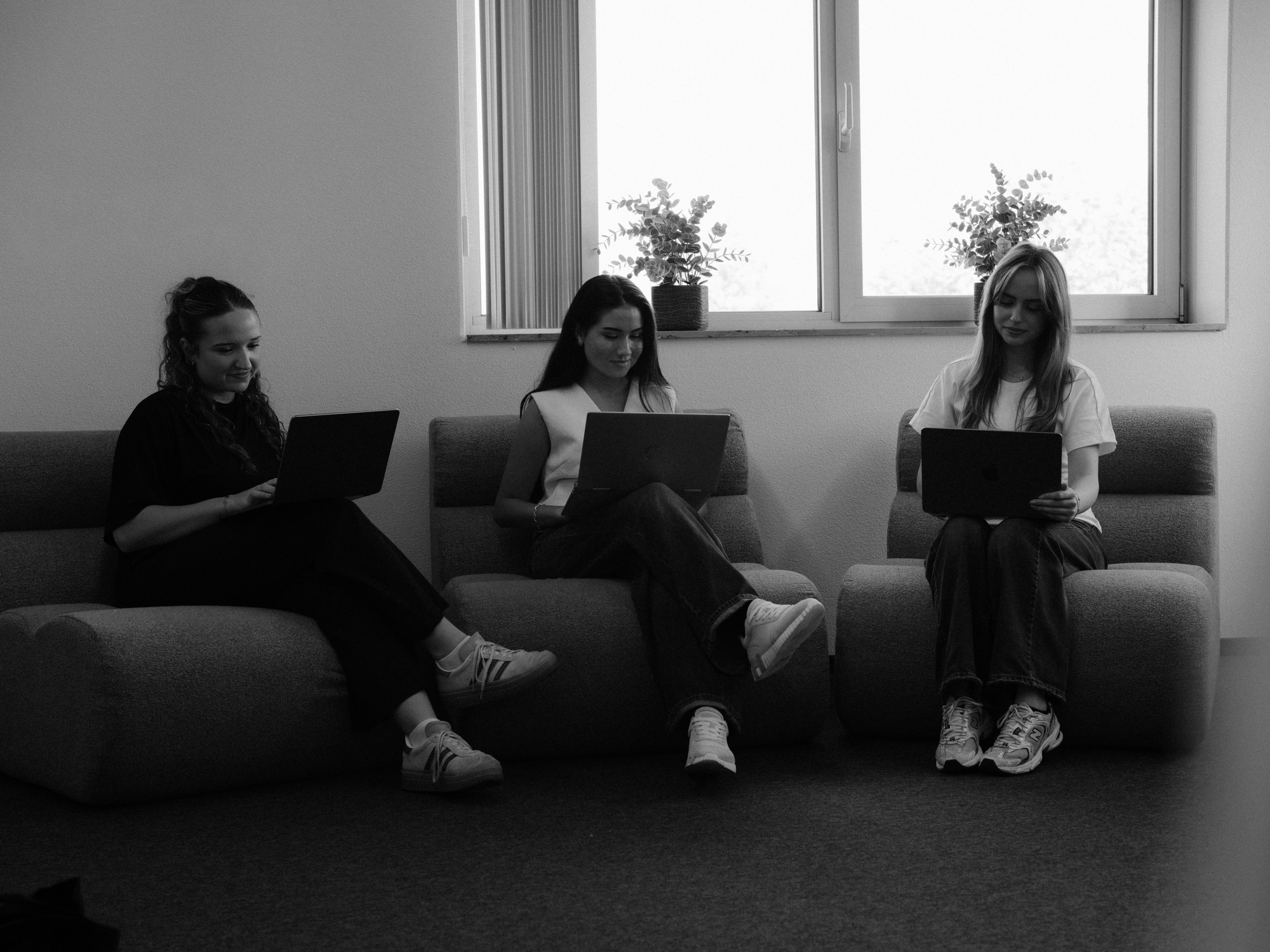Drie collega's werken op laptops op een bank