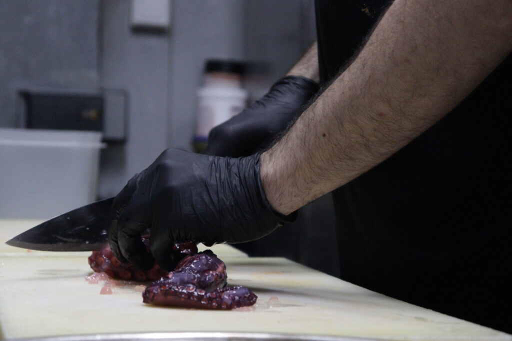 Chef van Vino Mío snijdt pulpo in de keuken